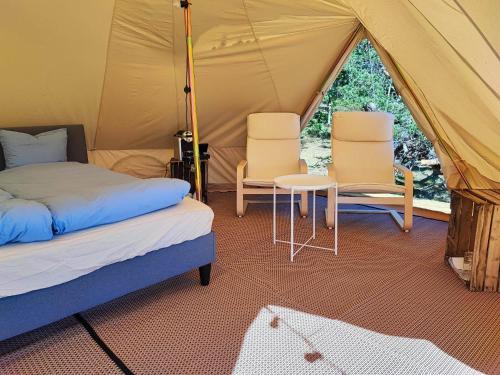 a tent with two chairs and a bed and a table at Unda Camping & Resort in Uddevalla