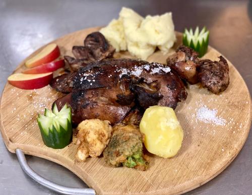 a plate of food with meat and vegetables on a table at Pensiunea Știuca Șchioapă in Băltenii de Sus