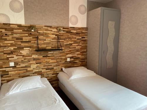 a bedroom with two beds and a brick wall at Hotel Restaurant Le Phare in Perros-Guirec