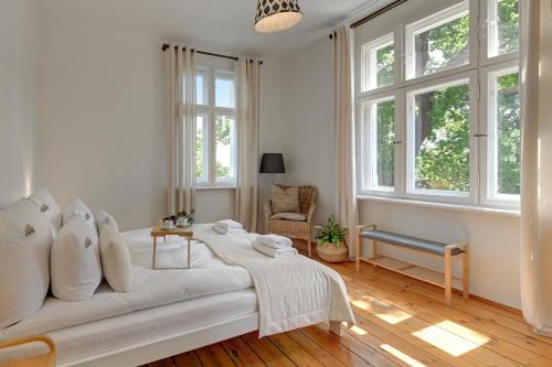 a white bedroom with a bed and windows at Downtown Apartments Sopot Jagiełły in Sopot