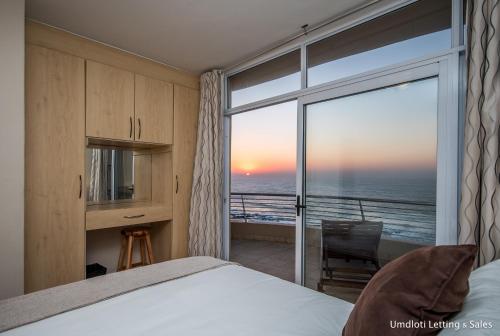 a bedroom with a bed and a view of the ocean at 5A Sugar Beach with Inverter in Umdloti