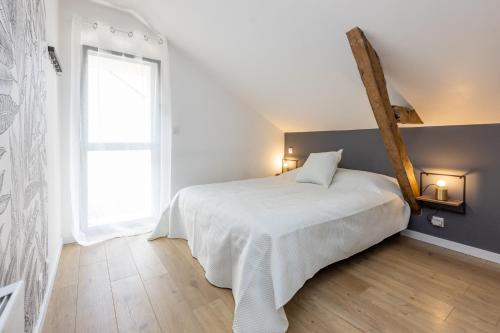 a bedroom with a white bed and a window at Le Cri de la Chouette - Appt avec terrasse in La Chapelle-Thouarault