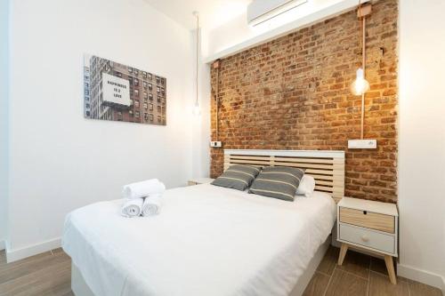 a bedroom with a white bed and a brick wall at Apartamento 1hab con estilo cerca de Ventas in Madrid