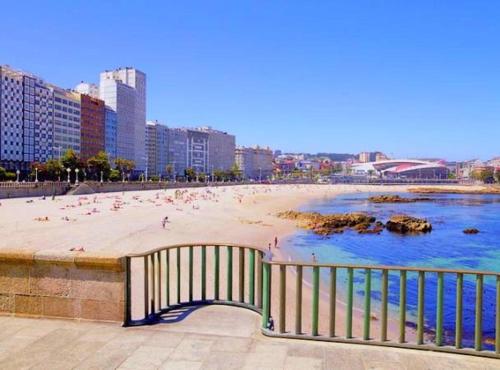 een strand met mensen op het zand en gebouwen bij Apartamento Breogan Coruña in A Coruña