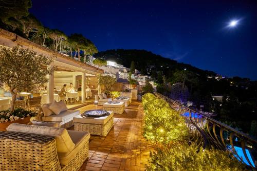 a patio with couches and chairs at night at Hotel La Minerva in Capri