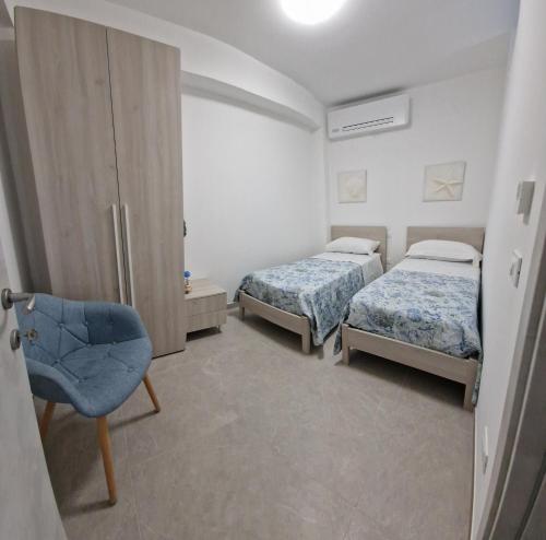 een slaapkamer met 2 bedden en een stoel. bij appartamento le onde in Terrasini