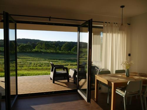 a dining room with a deck with a table and chairs at Klangor Mechowo in Mechowo