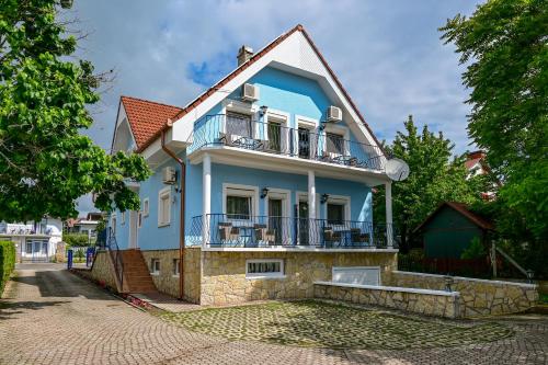 a blue house with a balcony on a street at Kék Lagúna Vendégház in Balatonfüred