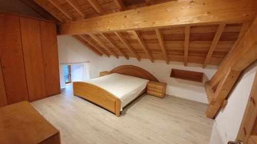 - une chambre avec un lit et un plafond en bois dans l'établissement La Ferme Les Digitales, à La Bresse