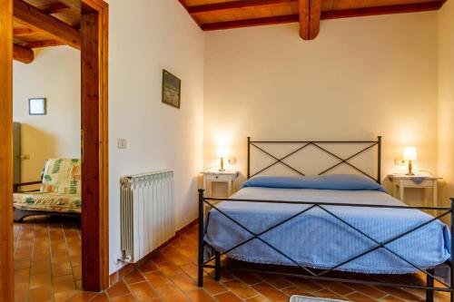 um quarto com uma cama com lençóis azuis e uma cadeira em Oleandro - Agriturismo La Fattoria em Grosseto