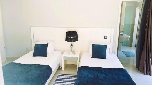 2 Betten in einem Hotelzimmer mit blauen Kissen in der Unterkunft Vilamoura Pine Hills Luxury Apartment in Quarteira