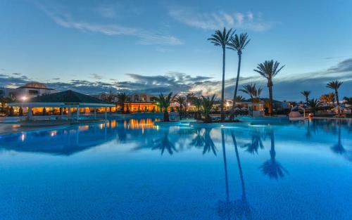 a large swimming pool with palm trees and buildings at Djerba Holiday Beach in Midoun