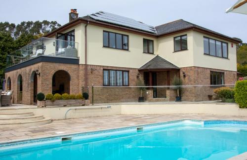 a house with a swimming pool in front of a house at Hewas Water House - Private Pool, Hot Tub & Games Room in Grampound