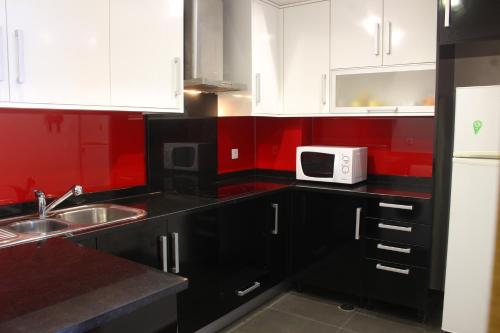 a kitchen with black cabinets and a white microwave at Casa da Dona Palmira in Fátima