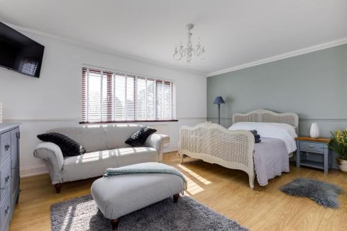 a bedroom with two beds and a couch and a tv at Hewas Water House - Private Pool, Hot Tub & Games Room in Grampound