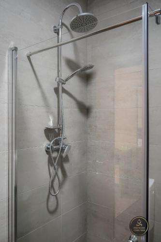 a shower with a shower head in a bathroom at Nosztalgia Resort in Vlăhiţa