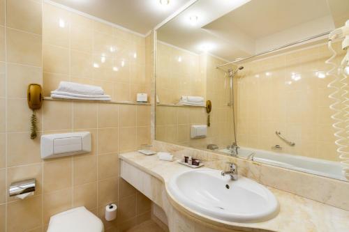 a bathroom with a sink and a mirror and a tub at Hotel Mazurkas in Ożarów Mazowiecki