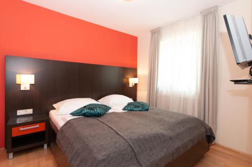 a bedroom with a bed with an orange wall at Residence Marina Garbin Apartment in Portorož