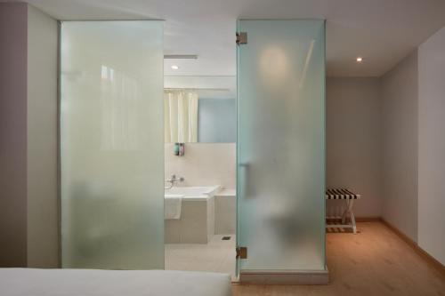 una puerta de cristal que conduce a un baño con lavabo en Ole Tai Sam Un Hotel, en Macau