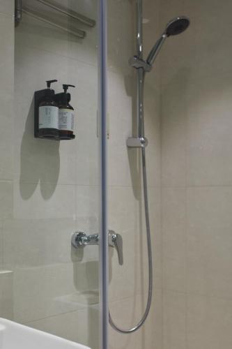 a shower with a glass door with two bottles on a shelf at Ole Tai Sam Un Hotel in Macau
