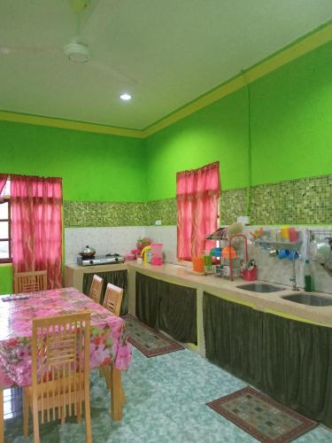 uma cozinha com paredes verdes, uma mesa e um lavatório em ROSMA HOMESTAY em Kampong Ru Sepuloh