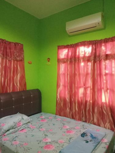 um quarto com paredes verdes e uma cama com cortinas cor-de-rosa em ROSMA HOMESTAY em Kampong Ru Sepuloh