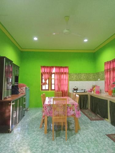 uma cozinha com uma mesa e uma parede verde em ROSMA HOMESTAY em Kampong Ru Sepuloh