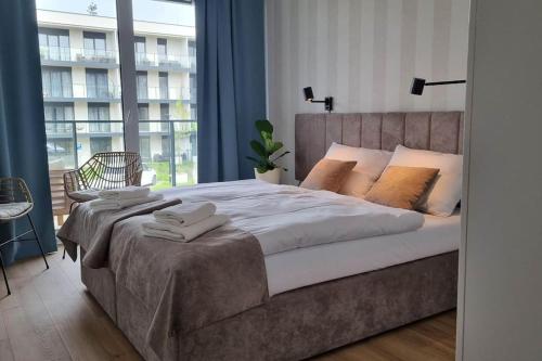 ein Schlafzimmer mit einem großen Bett und einem großen Fenster in der Unterkunft Wspaniały apartament & SPA nad morzem in Dziwnów