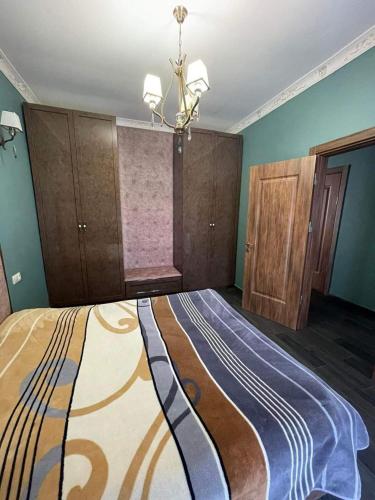 - une chambre avec un grand lit aux murs bleus et un lustre dans l'établissement Kvartita sofia, à Kobuleti