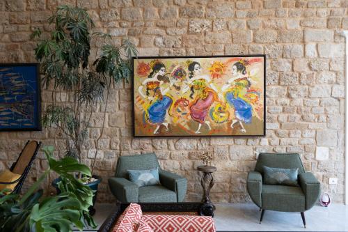 a painting hanging on a brick wall with two chairs at Dar Alice in Soûr