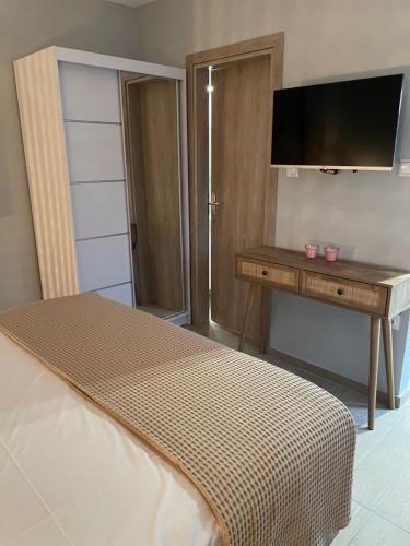 a bedroom with a bed and a desk with a television at Barbara’s House,New Superior Central Studio in Nea Kallikrateia