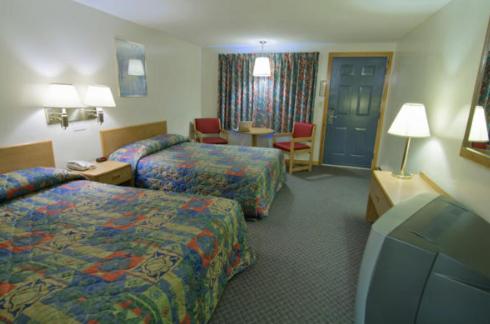 Cette chambre d'hôtel comprend deux lits, une table et des chaises. dans l'établissement Americas Best Value Inn Biddeford, à Biddeford