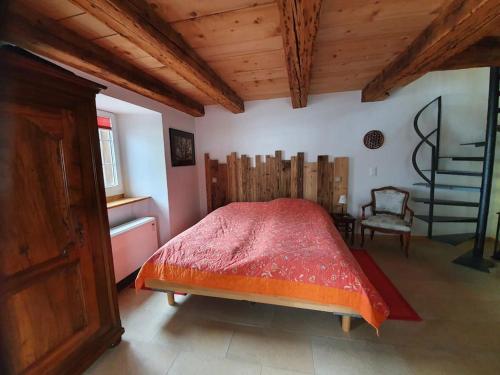 a bedroom with a red bed and a chair at Au Château in Lajoux