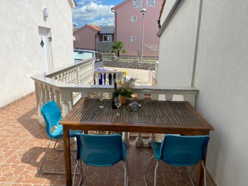 a wooden table on a balcony with blue chairs at Apartments Michael & Petra , Omisalj, Insel Krk, Kroatien in Omišalj