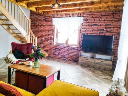 a living room with a brick wall and a television at Wierchy Beskidu in Dobra