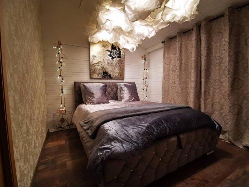 a bedroom with a large bed and a chandelier at Chalet, lodge, Cottage, avec spa au bord de l'eau in Prouilly
