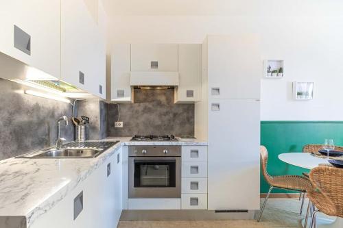 eine Küche mit weißen Schränken, einer Spüle und einem Tisch in der Unterkunft Teatro Ariston, Elegante Appartamento Centrale in Sanremo