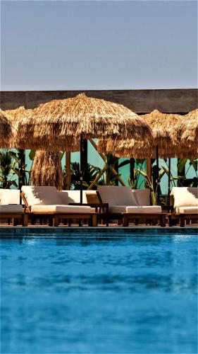 a swimming pool with lounge chairs and straw umbrellas at Voger Bodrum by The Sea in Yalıkavak