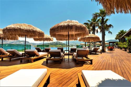 a deck with chairs and umbrellas on a beach at Voger Bodrum by The Sea in Yalıkavak