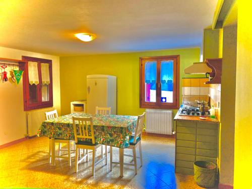 een keuken met een tafel met stoelen en een koelkast bij B&B Casa Linda in Pradipozzo