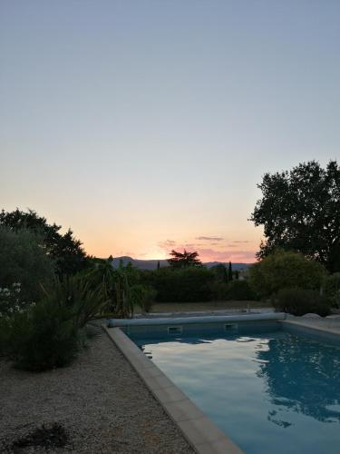 une piscine avec un coucher de soleil en arrière-plan dans l'établissement Domaine de l'Arbre Doré, à Lèzan