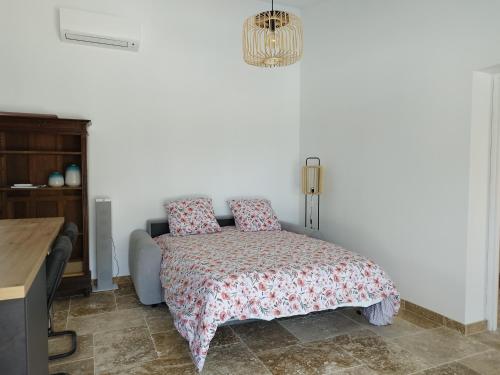um quarto com uma cama, uma mesa e um lustre em Domaine de l'Arbre Doré em Lèzan