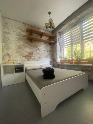 1 dormitorio con cama blanca y pared de ladrillo en OLD CITY Loft, en Öskemen