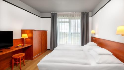 a hotel room with two beds and a television at Hunguest Bük - ex Répce és Répce Gold in Bük
