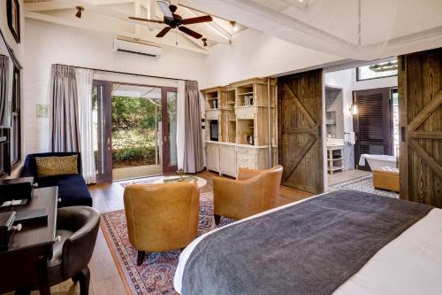 a bedroom with a bed and a desk and chairs at Mbano Manor Hotel Victoria Falls by Mantis in Victoria Falls