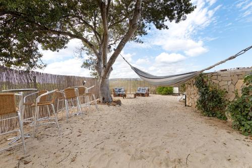 a hammock sitting under a tree in the sand at Casa Arinto in Palmela
