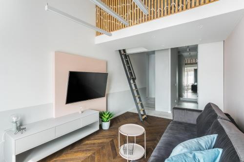 Premium Apartment in Kossak Residence في كراكوف: غرفة معيشة مع أريكة وتلفزيون بشاشة مسطحة