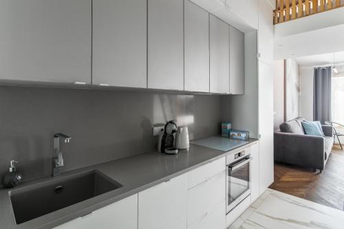 Premium Apartment in Kossak Residence في كراكوف: مطبخ بدولاب بيضاء ومغسلة سوداء