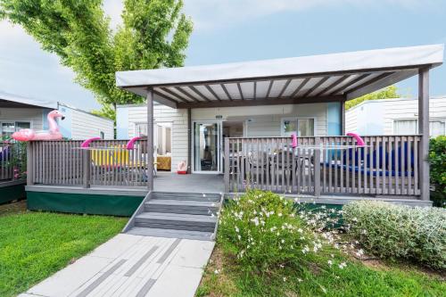 a house with a porch with awning and a playground at Camping Village Garden Paradiso in Cavallino-Treporti