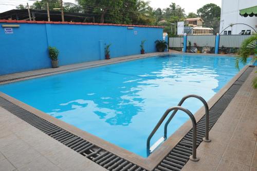 a large swimming pool with a blue wall and stairs at Nelly Star Hotel in Vavuniya